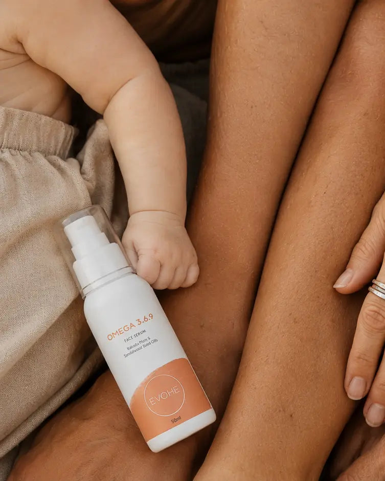 Two people sitting together with a baby, surrounded by two bottles of a product.