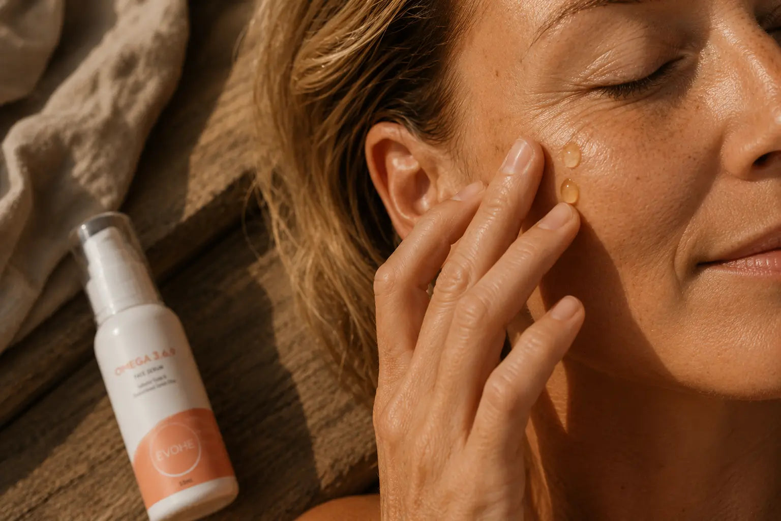 Woman applying sunscreen to her face with a bottle of sunscreen next to her.